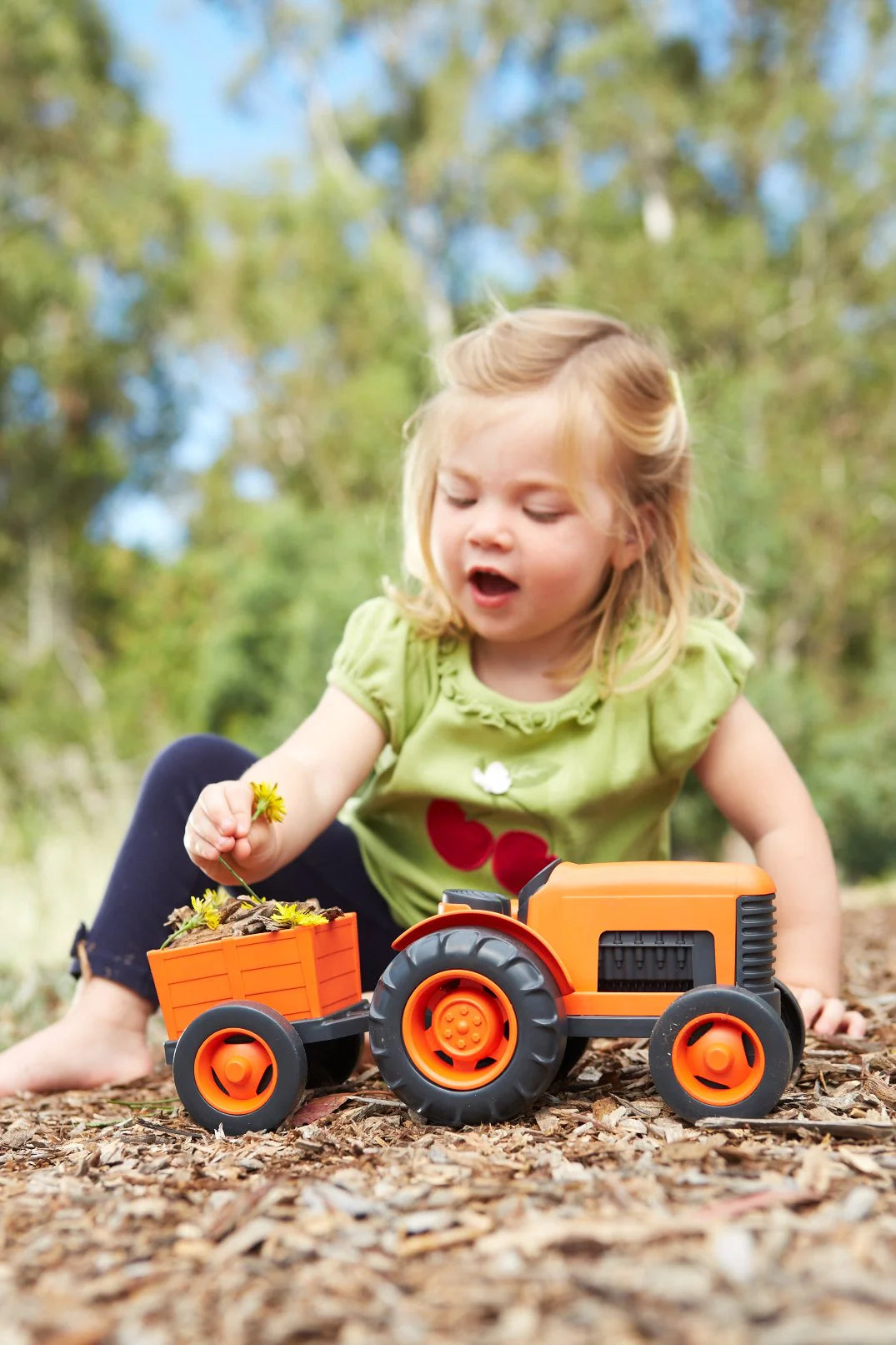 Child playing with a toy tractor and trailer outdoors