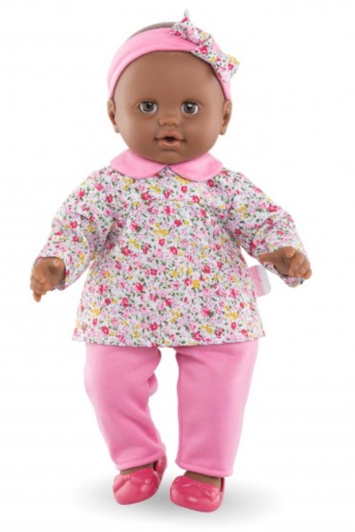 A large baby doll with a brown body, wearing a floral top and pants, and a headband. The doll has a soft, realistic appearance with a sleeping eye detail.