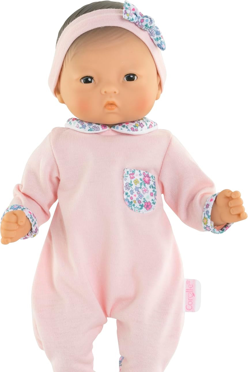 Baby doll in pink outfit with floral details on a white background