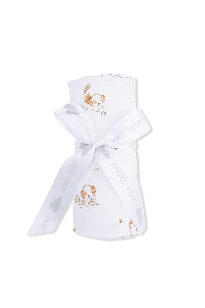 Puppies on white blanket rolled with ribbon tied 